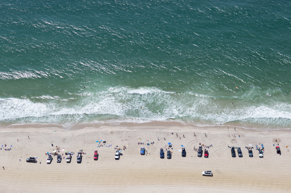 An aerial view of the beach with cars on it