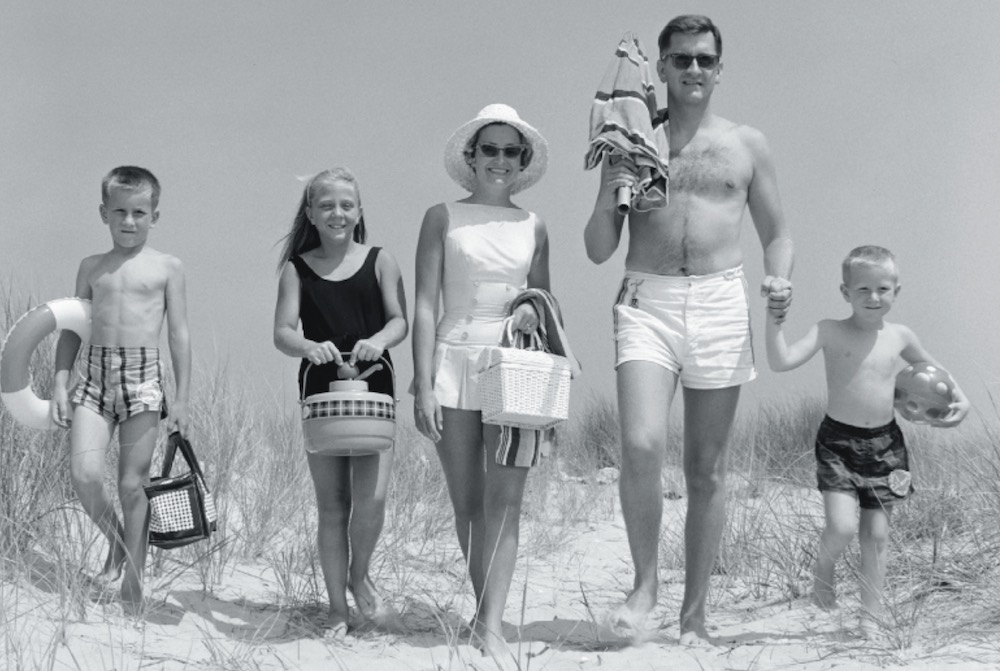 Family walking together on a beach carrying buckets and beach gear